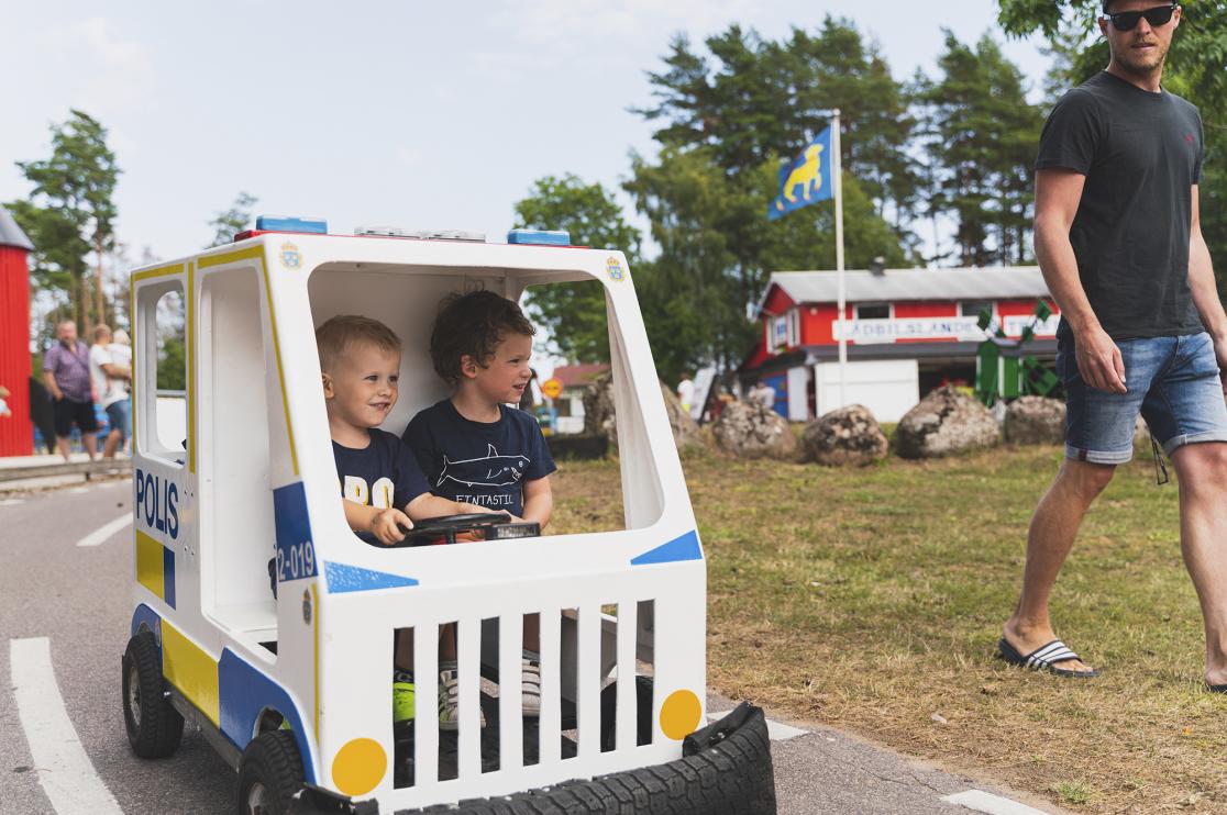Två barn i en polislådbil.