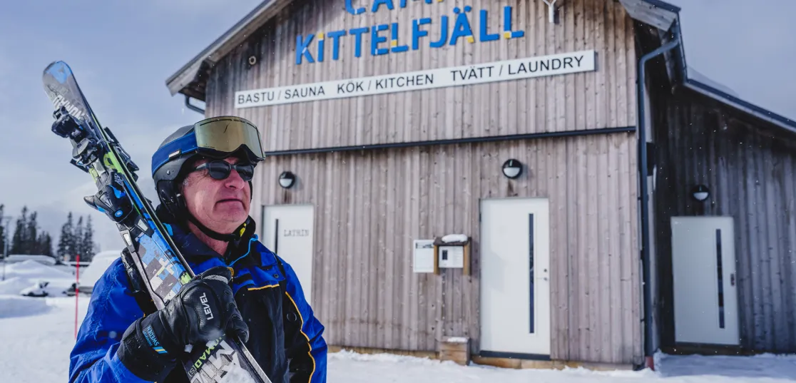 Skidåkare framför servicehus på Camp Kittelfjäll