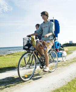 Två personer cyklar på grusväg längs havet.