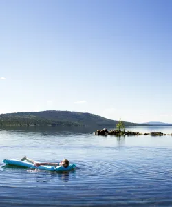 Ett barn ligger på en luftmadrass på en luftmadrass och paddlar på blått vatten.