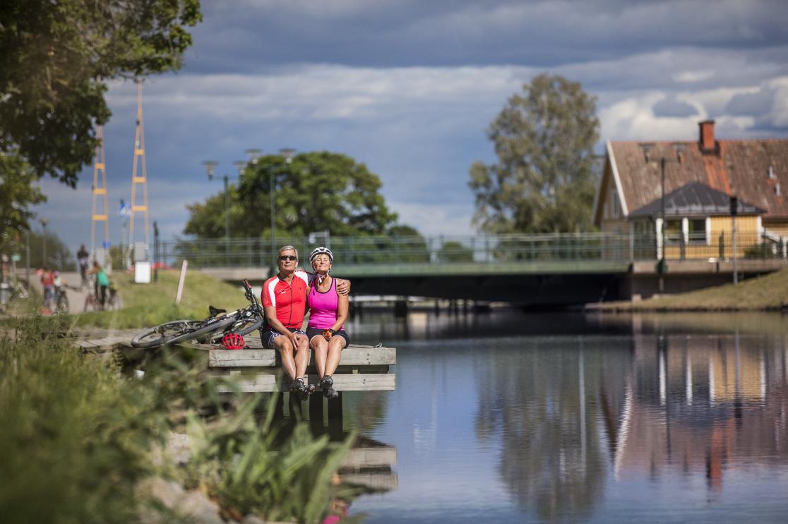 Två personer solar på en brygga intill Göta kanal.
