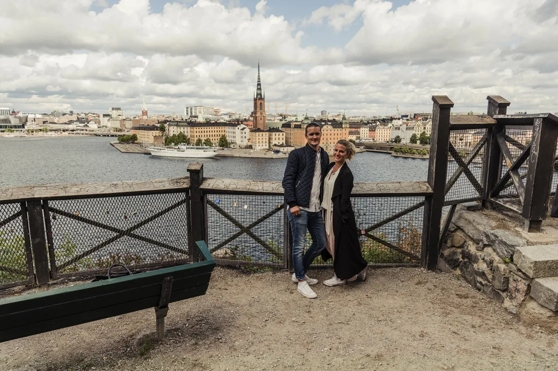 Par på en höjd vid ett staket, i bakgrunden vy över Stockholm.