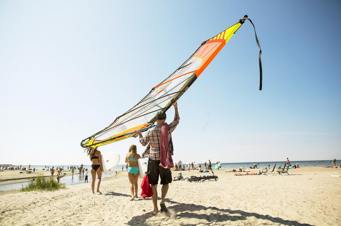 Man med vindsurfingbräda på strand