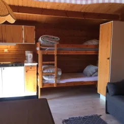 Interiör av stuga med våningssäng, köksdel och sittplats